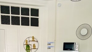 A modern kitchen with a wooden table, two white bar stools, a refrigerator, and a wall-mounted clock. - Urban Zen Appart in the city center✨ (Pointe-à-Pitre)