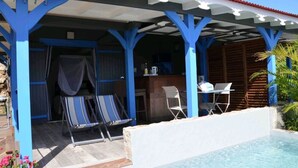 Ein überdachter Außenbereich mit Pool, blauen Säulen und Barbereich.