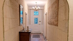Een hal met een gewelfde plafond, een houten dressoir en een deur met glas-in-loodramen.