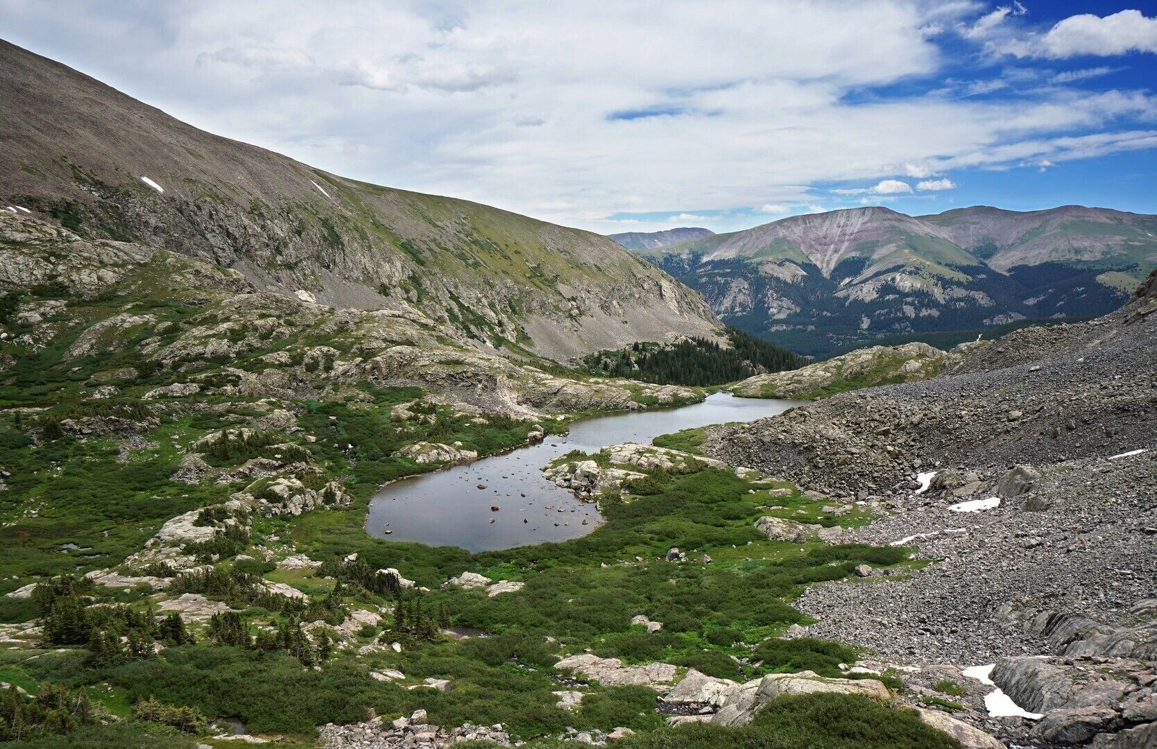 Paisagem montanhosa com um lago e vegetação ao redor.