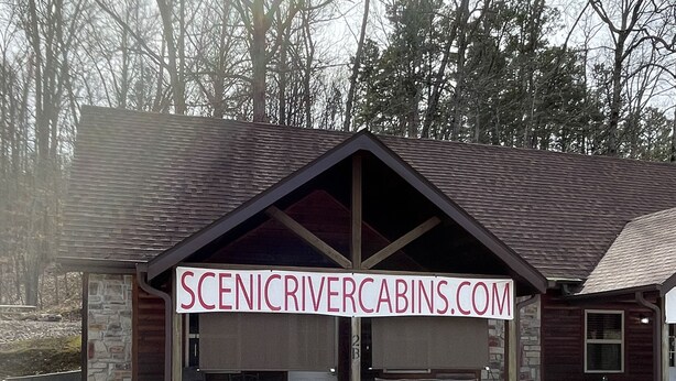 Une cabane avec une allée en gravier et un panneau indiquant l’adresse suivante : « SCENICRIVERCABINS.COM ».