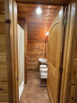 A wooden-paneled bathroom with a sink, towel rack, and a shower curtain.