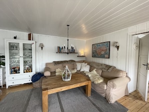 Un salon chaleureux avec une table basse en bois, un canapé beige et un meuble avec des portes en verre.