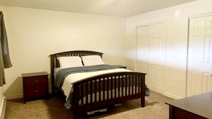 Un dormitorio con una cama individual, una mesita de noche, un aparador y un armario de dos puertas.