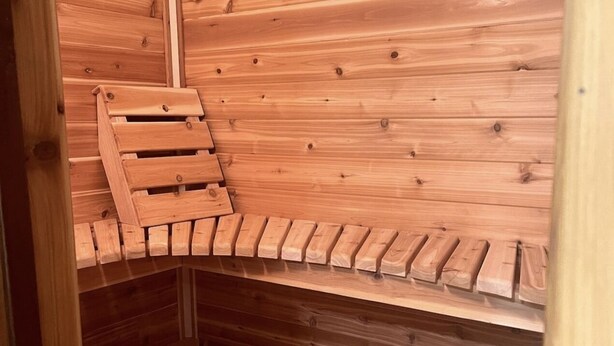 Una sauna de madera con techo inclinado y un banco de madera.