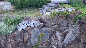 Ein Haus mit rotem Anstrich, einer Steinmauer und einer Holztreppe, die zum Eingang führt.