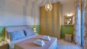 A bedroom with a bed, bedside tables, a hanging light fixture, a wardrobe, and a mirror. - Elkysti Crete Superior Apartment "Nikos" (Kreta)