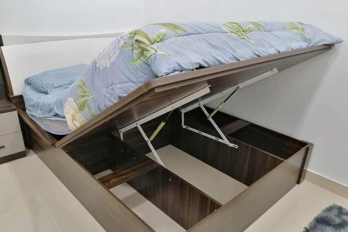 A bed with a wooden frame and a pull-out storage drawer underneath.