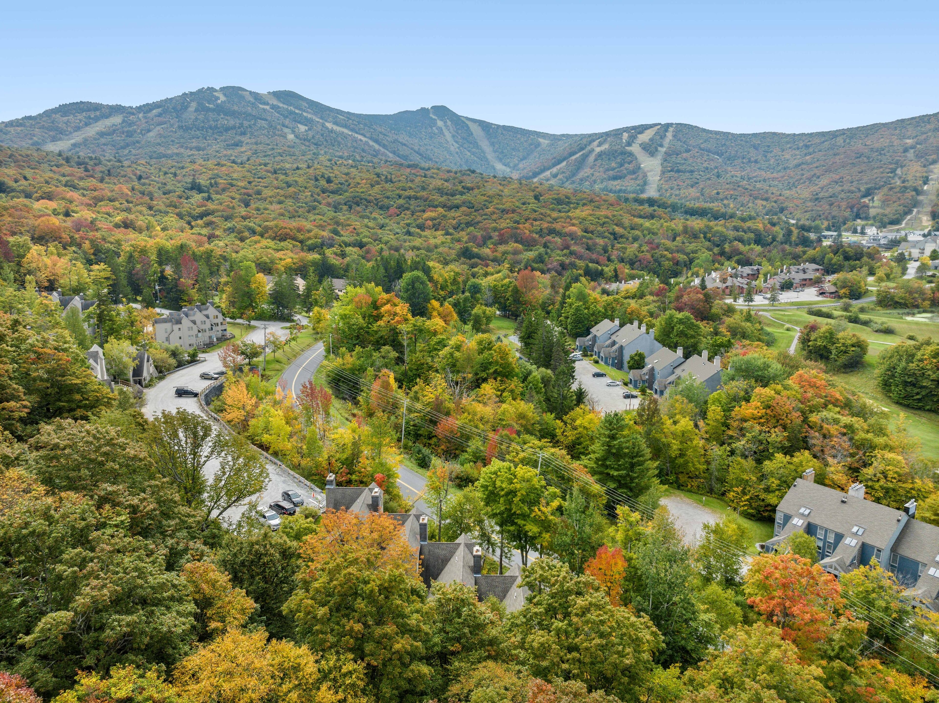 A residential area with houses, roads, and a mountainous backdrop.