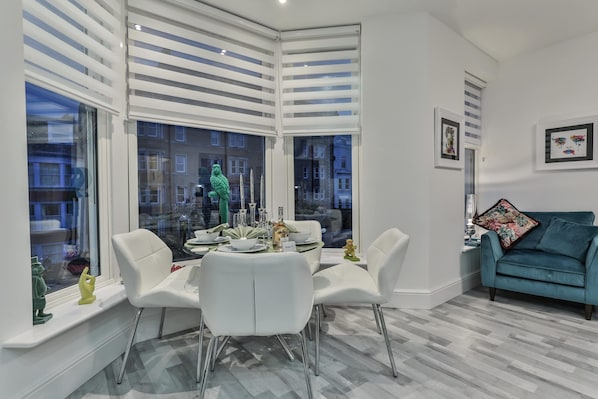 Relax in this stylish living room with a dining area, featuring a comfortable sofa and dining table.