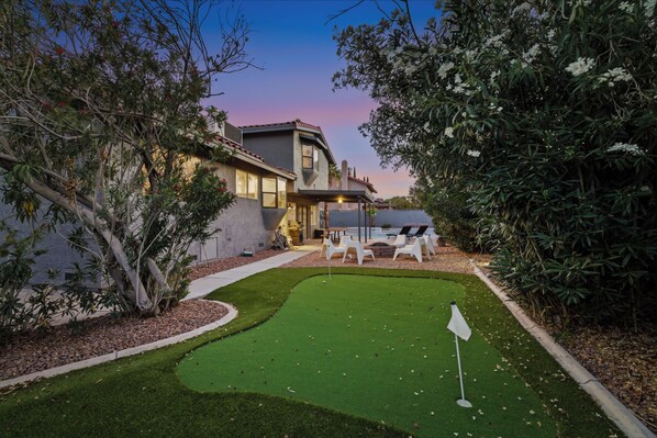 A modern house with a well-maintained lawn and a putting green. - Bright! Contemporary Modern 4BR, Lg Backyard w/New Spa & Pool + Mini Putting! (Las Vegas)