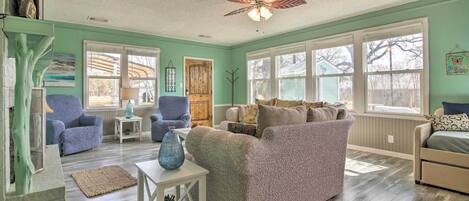 A cozy living room with a teal wall, wooden flooring, and a ceiling fan. There are two sofas, a coffee table, and a side table.