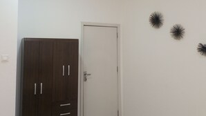 Een kamer met een donkerhouten garderobe, een witte deur en drie zwarte decoraties aan de muur.