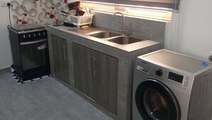 Een praktische keuken met een ingebouwde wasmachine, kookplaat en gootsteen.