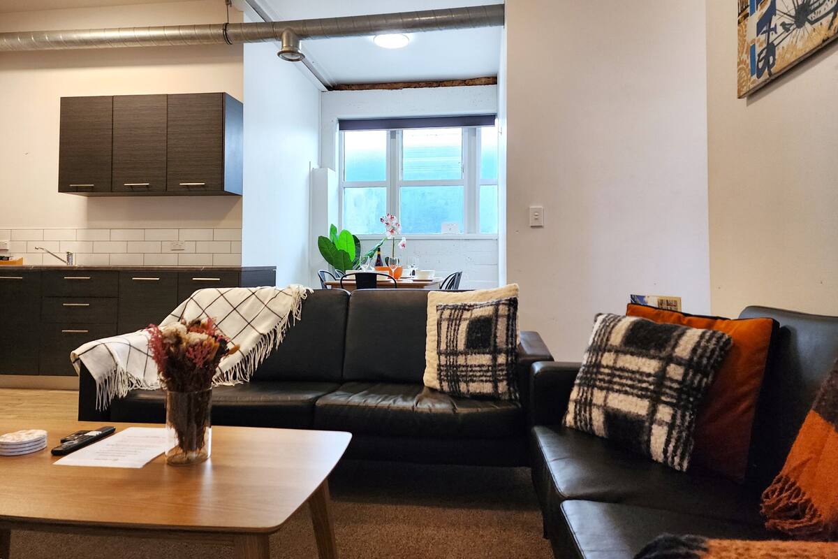 A compact living space with a kitchenette, a dining area, and a seating area with a sofa and a coffee table.