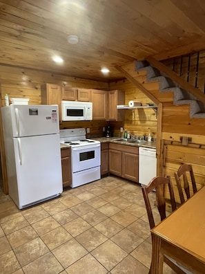 A kitchen with wooden cabinets, a refrigerator, a stove, a microwave, and a dishwasher.