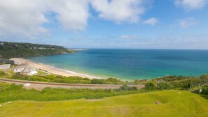 Un paysage côtier avec une plage, une maison et une voie ferrée.