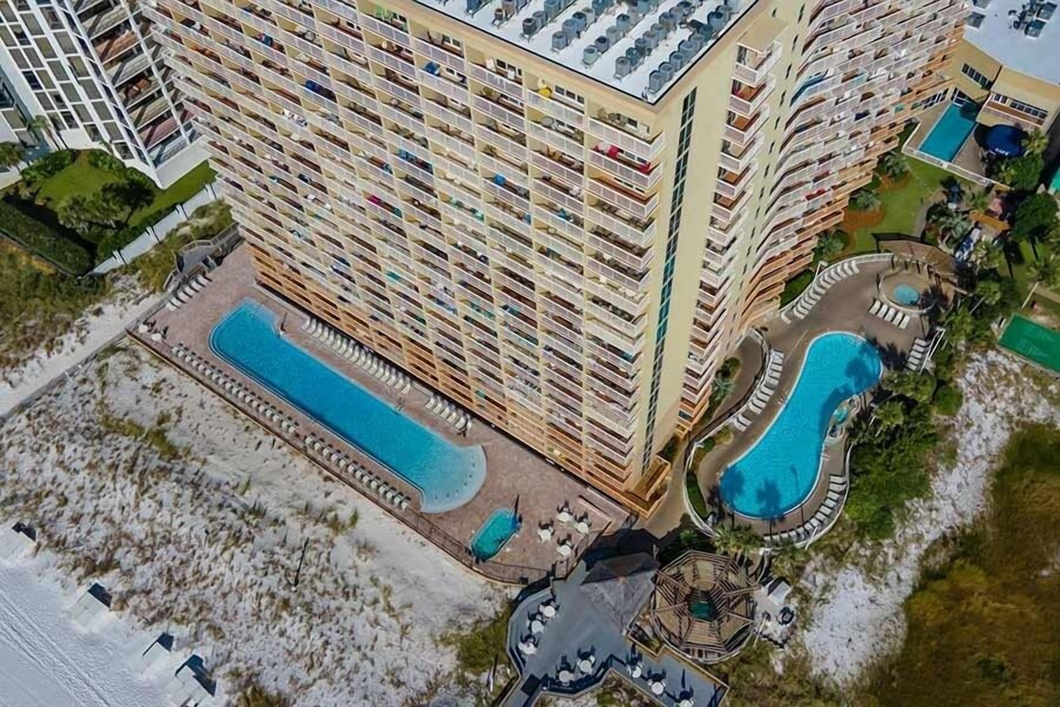 A high-rise hotel with multiple balconies, a central swimming pool, and a smaller pool area.