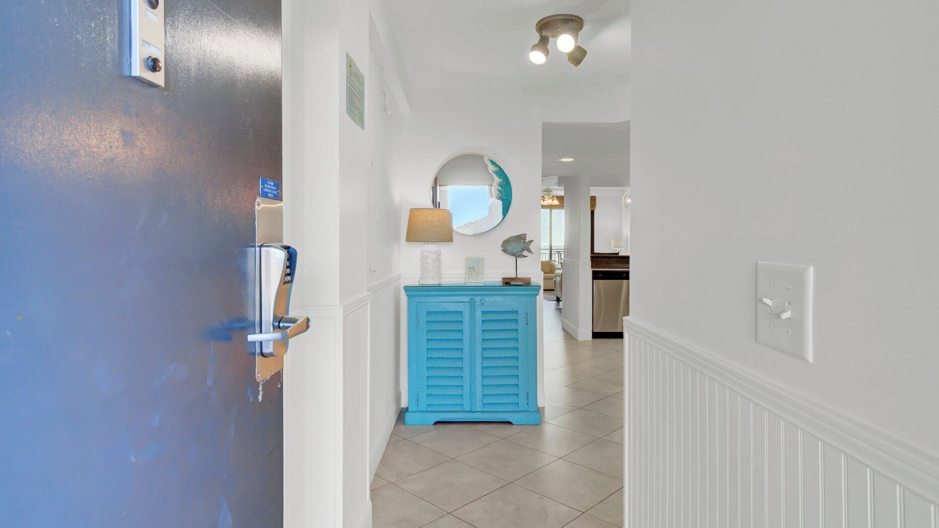A hallway with a blue cabinet, a white door, and a ceiling light fixture.