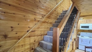 Un escalier en bois avec une rampe, des marches recouvertes de moquette et une table avec des chaises à l’intérieur d’une cabine.