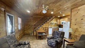 Un intérieur de chalet chaleureux avec des murs en bois, un coin repas, un canapé et une cuisine.