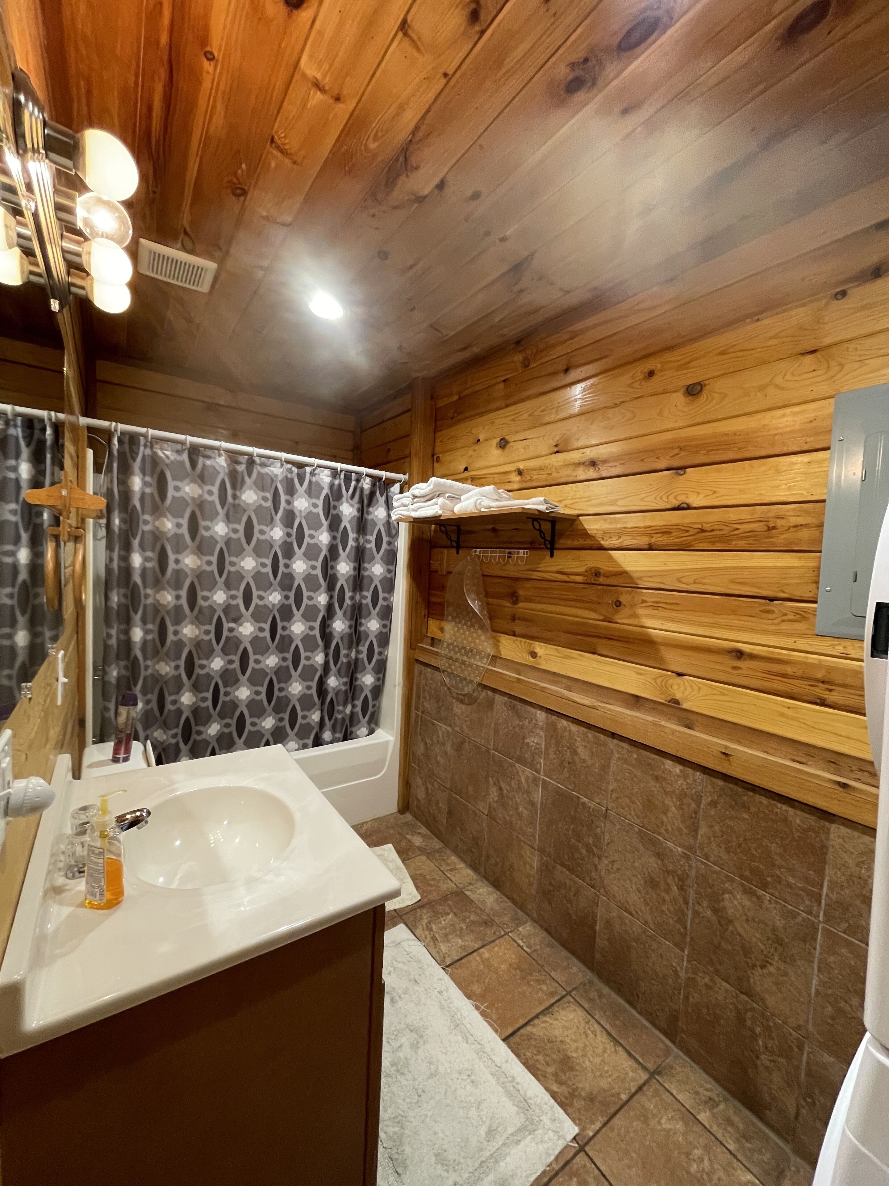 Een houten badkamer in een chalet, met een wastafel, spiegel en douche.