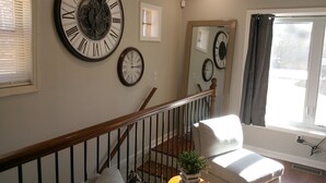 A staircase with a wooden handrail, a white cushioned bench, and a small wooden table with a plant. - Quaint home in a quiet neighborhood!! Near airport! (East Point)