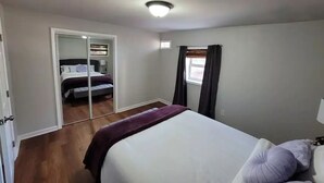 A bedroom with a bed, a mirror, a window with curtains, and a ceiling light. - Quaint home in a quiet neighborhood!! Near airport! (East Point)
