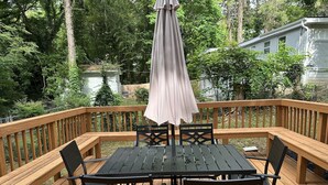 A wooden deck with a table and chairs, surrounded by a wooden railing. - Quaint home in a quiet neighborhood!! Near airport! (East Point)