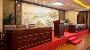 A reception area with a wooden reception desk, a large mural, and a red carpeted floor.