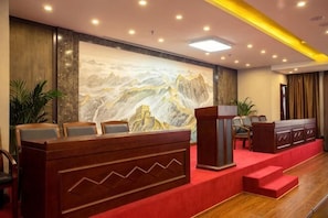 A reception area with a wooden reception desk, a large mural, and a red carpeted floor.