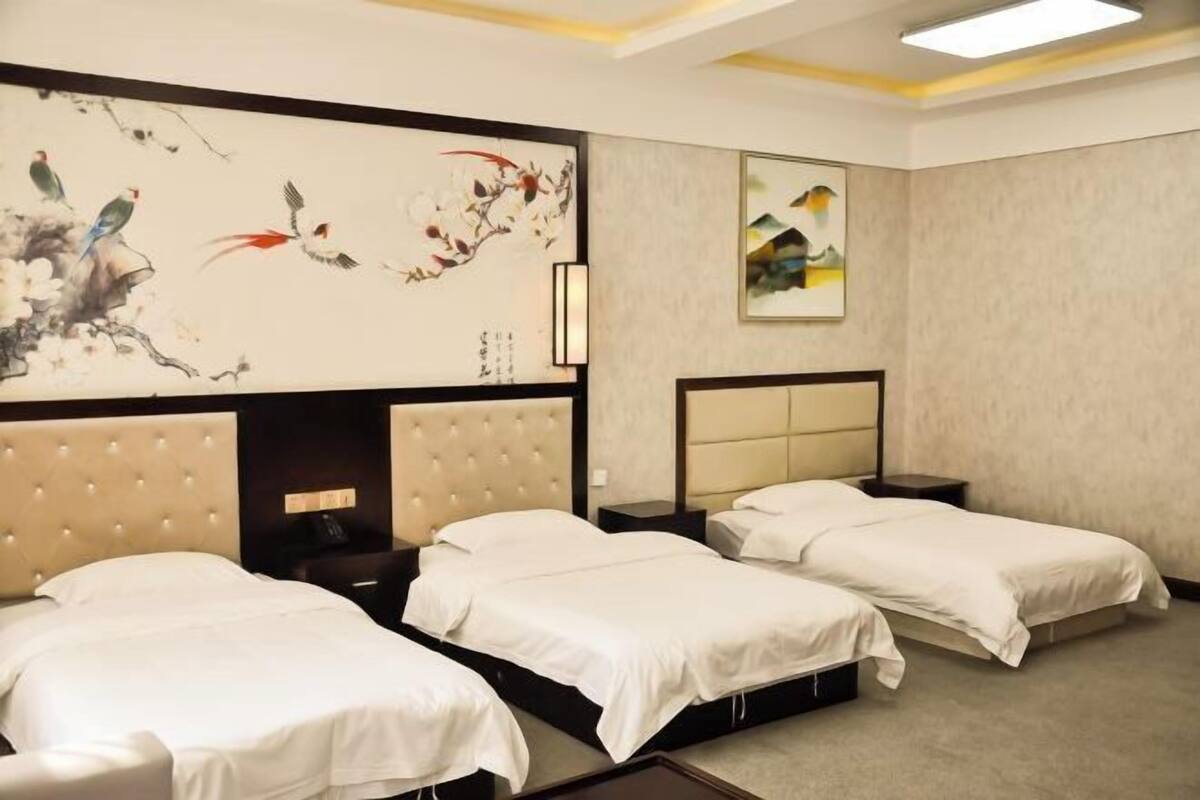 A hotel room with two beds, a large wall painting, and a framed picture.