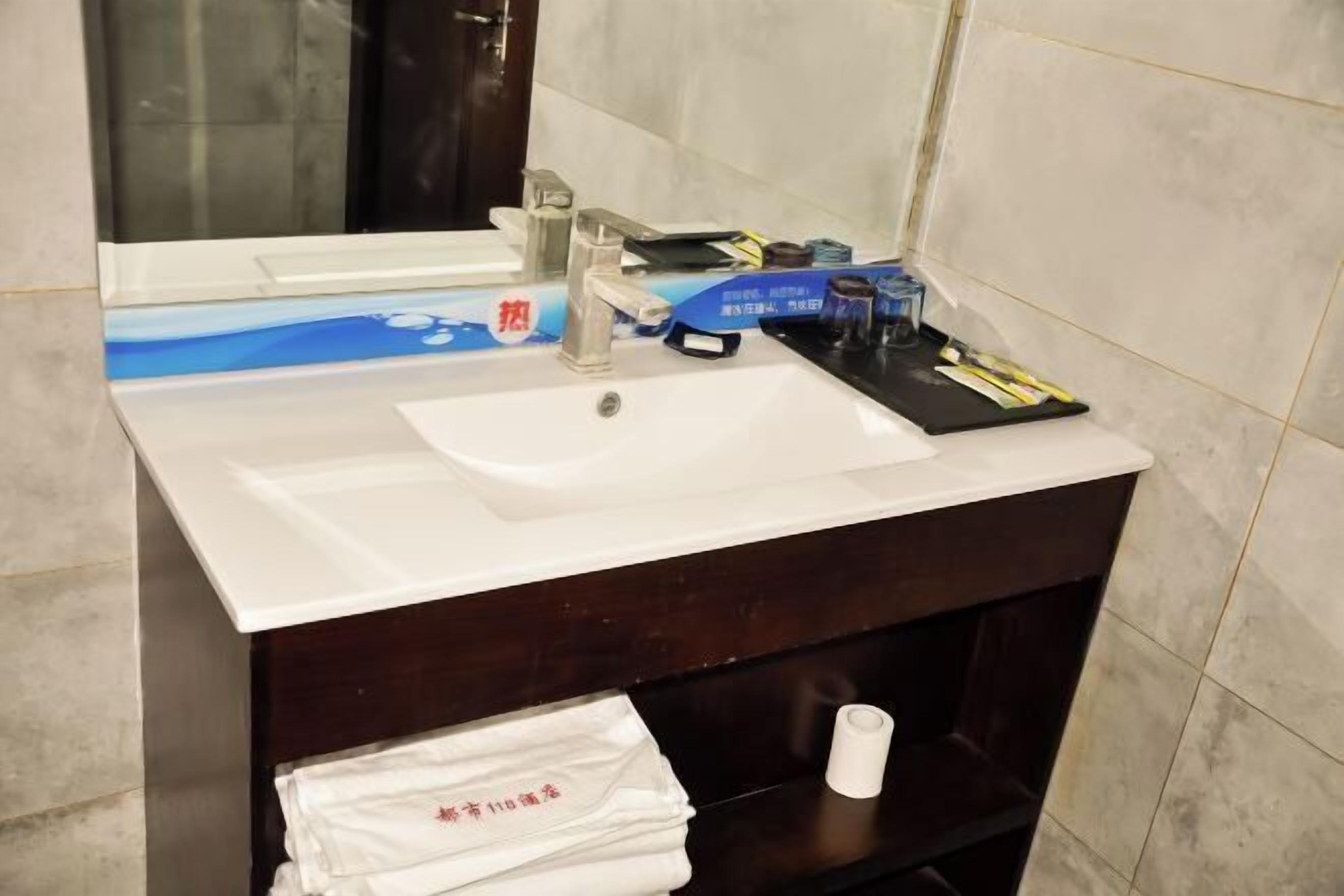 A bathroom with a white sink, mirror, and dark wooden vanity.