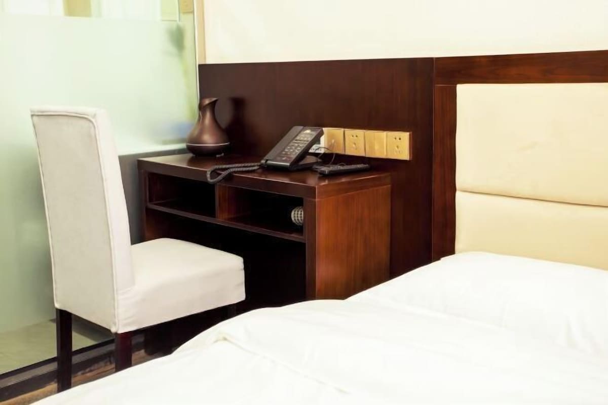 Une chambre d’hôtel avec un lit, un bureau avec un téléphone et une chaise.