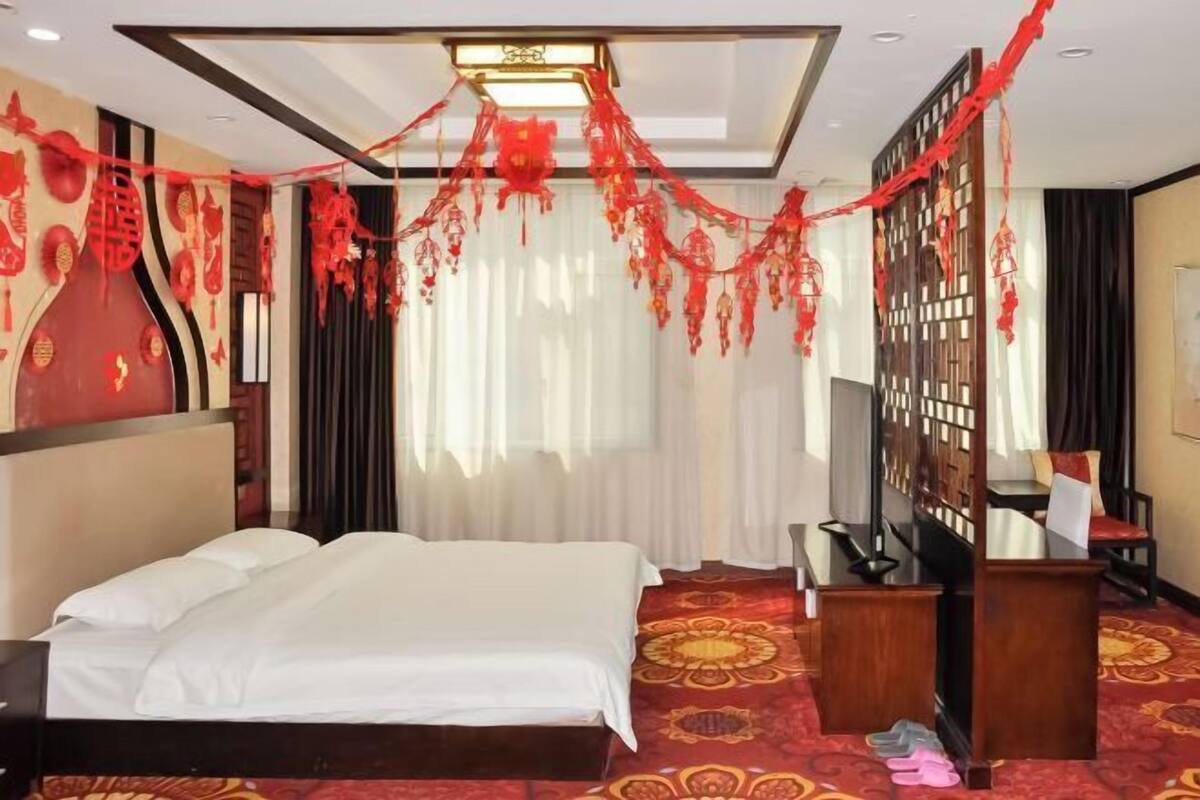 A hotel room with a bed, a desk, and a TV.