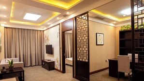 A modern living room with a sofa, a TV, a dining table, and a decorative partition.
