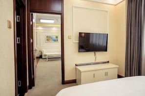 Une chambre d’hôtel comprenant un lit, un téléviseur fixé au mur, un petit bureau et une armoire.