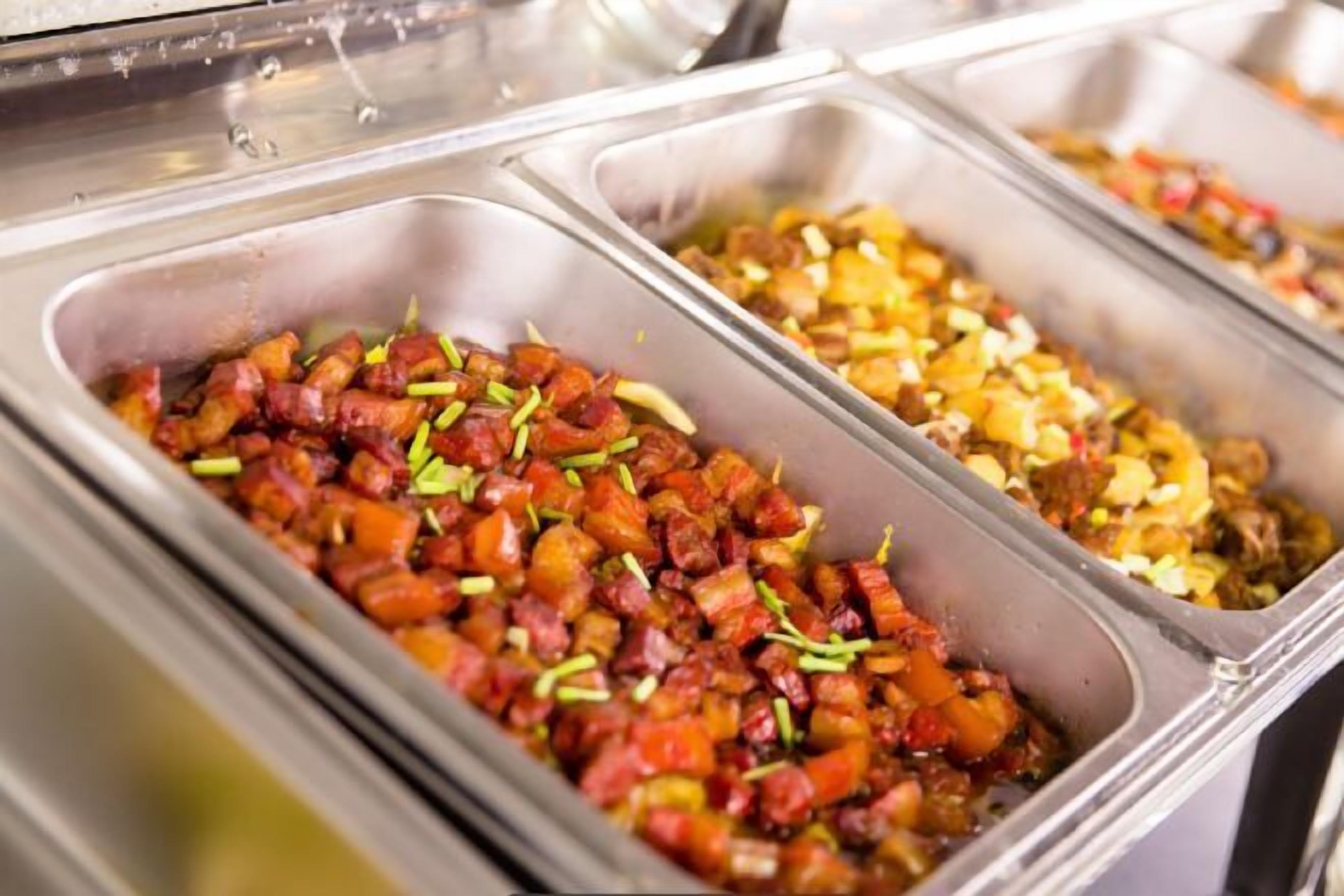 A buffet with various dishes, including diced vegetables and meats.