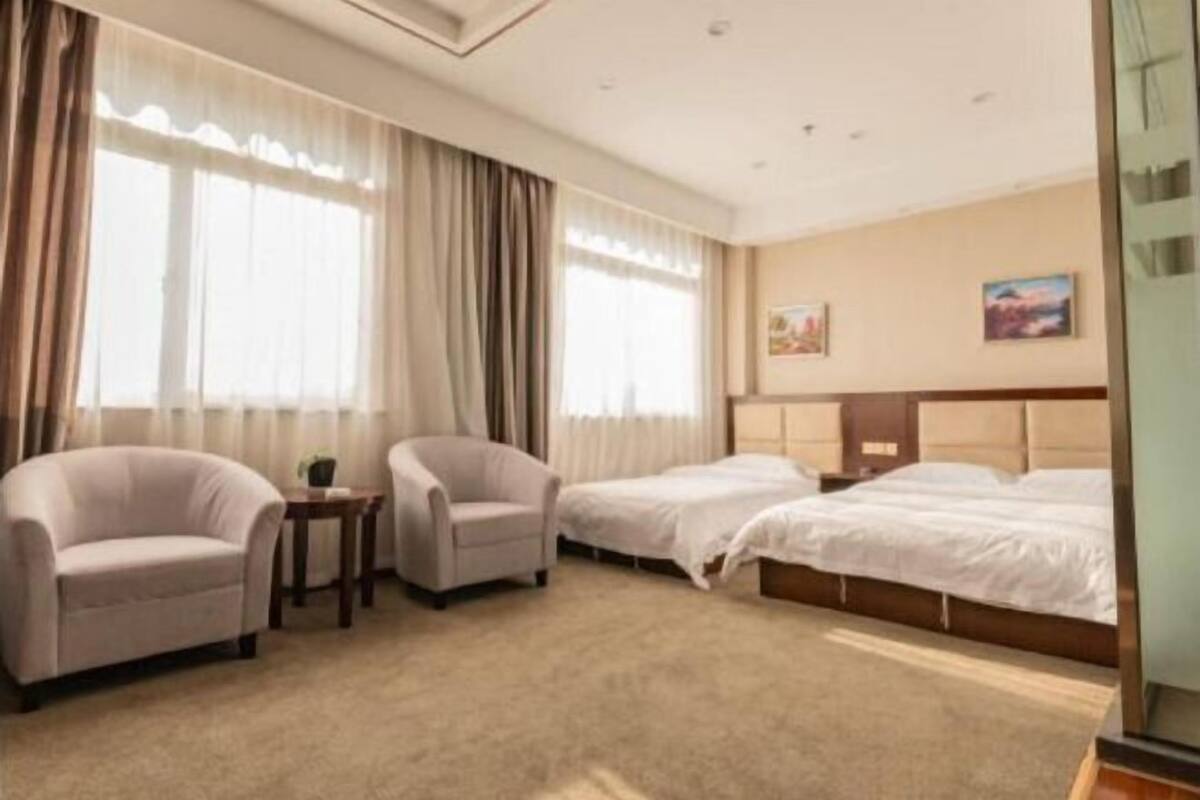 A hotel room with two beds, a sofa, a small table, and a painting on the wall.