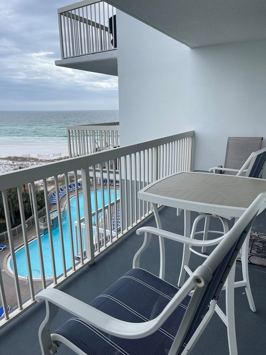 Un balcón con vista a una piscina y una playa.