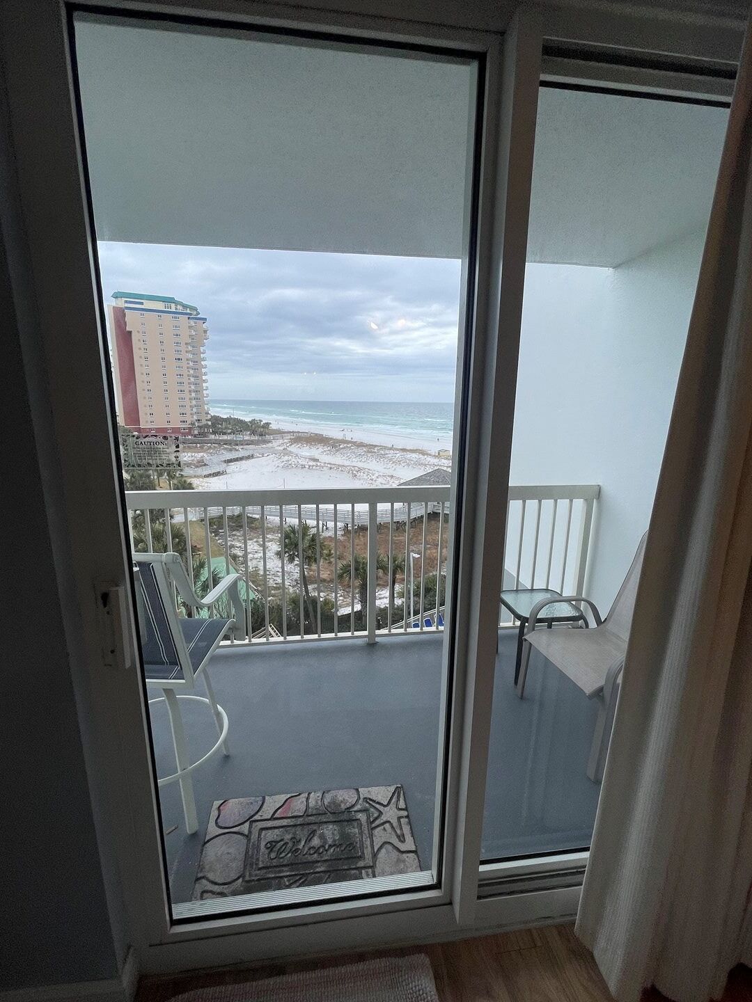 A balcony with a view of a beach and a hotel building.