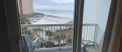 A balcony with a view of a beach and a hotel building.