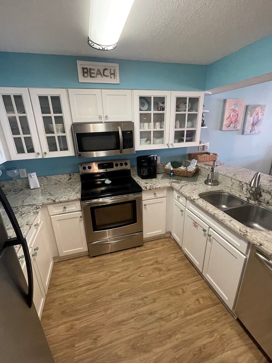 A kitchen with white cabinets, a stainless steel oven, a microwave, and a coffee maker.