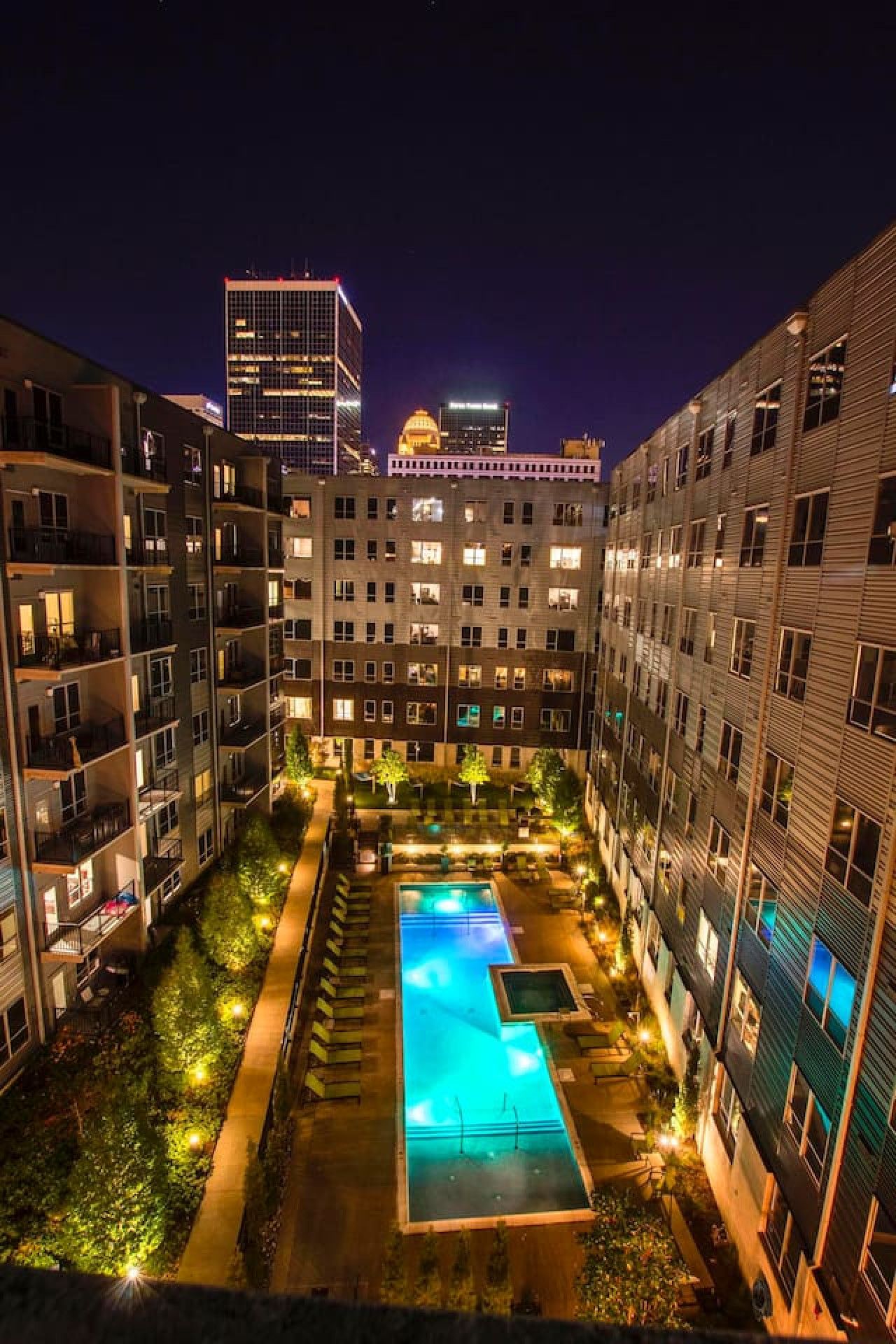A multi-story hotel with a central courtyard featuring a swimming pool, surrounded by balconies and a landscaped garden.
