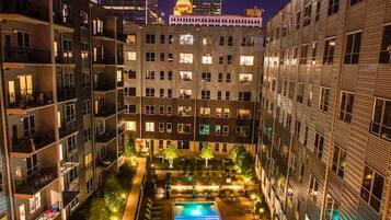 A multi-story hotel with a central courtyard featuring a swimming pool, surrounded by balconies and a landscaped garden.