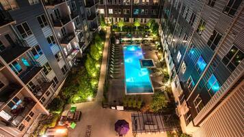 A rooftop pool area surrounded by residential buildings with balconies and outdoor seating.