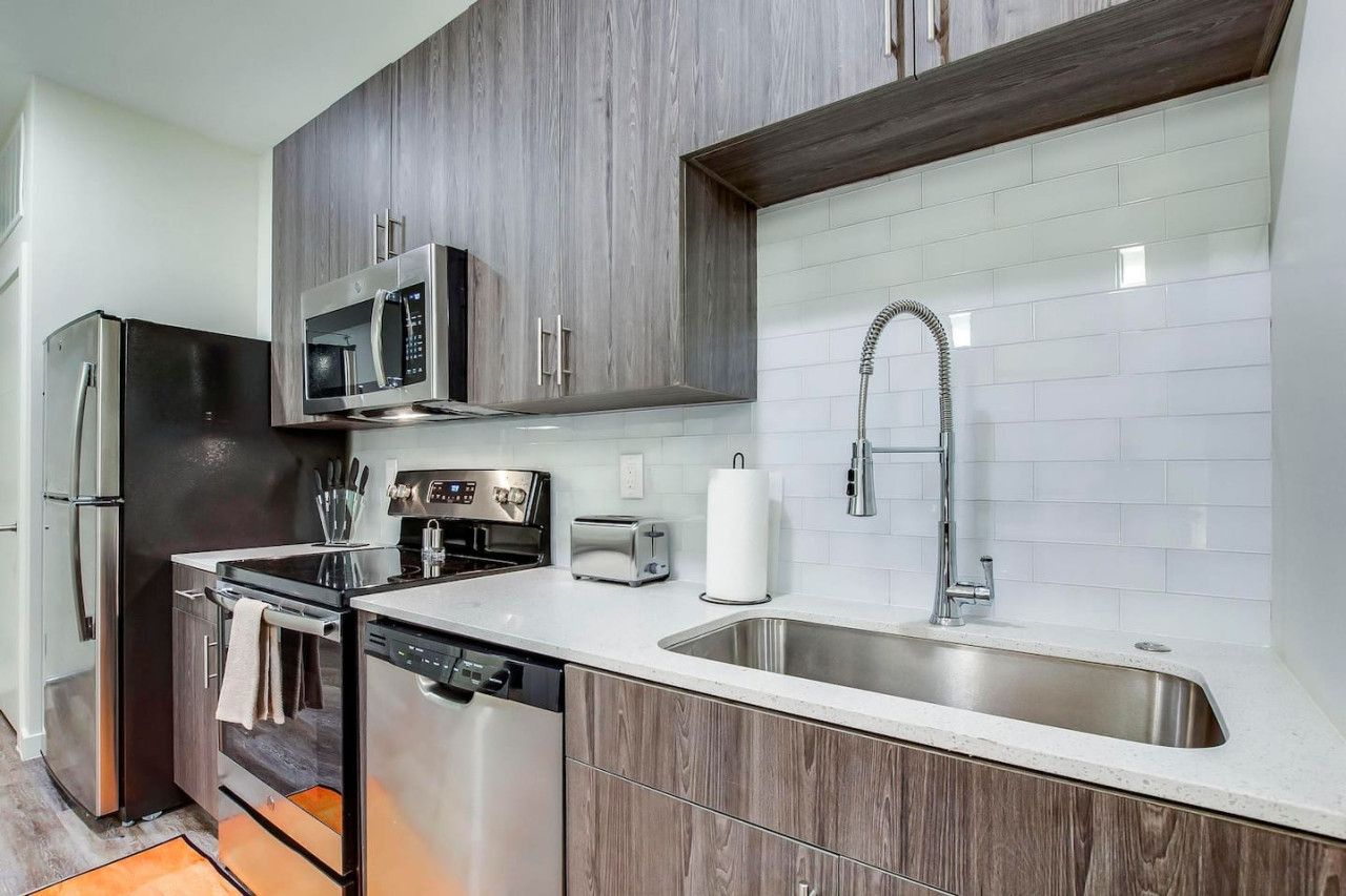 A modern kitchen with stainless steel appliances, a dishwasher, a microwave, and a sink.