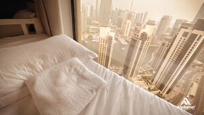 Camera d'hotel con un letto, cuscini e vista sulla città.
