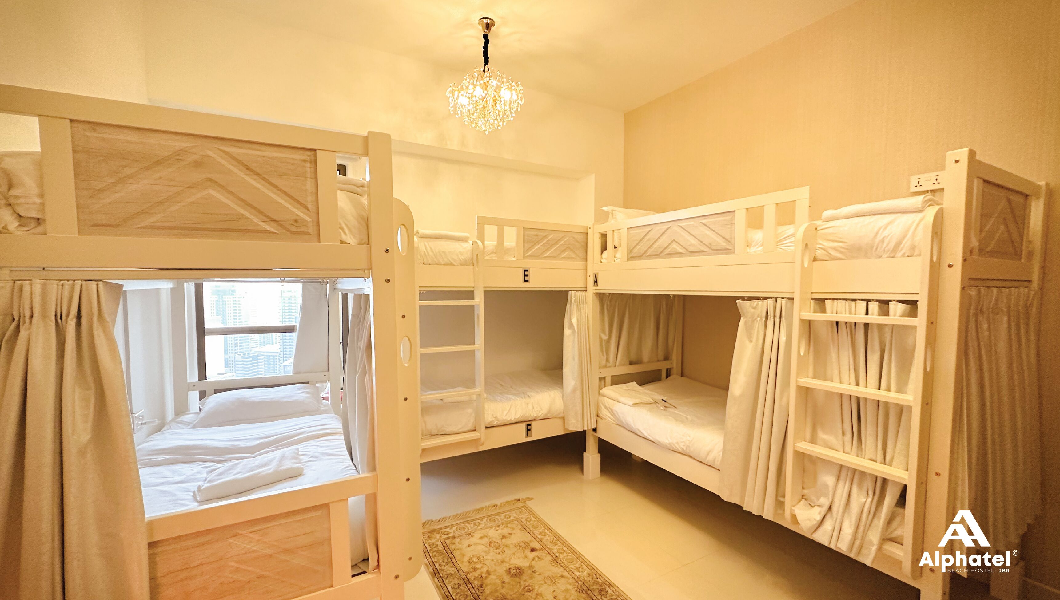 Una camera con un letto a castello, un lampadario, una finestra con tende e un tappeto sul pavimento.