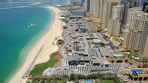 Una vista aerea di una città costiera con spiaggia, grattacieli e un mix di edifici residenziali e commerciali.